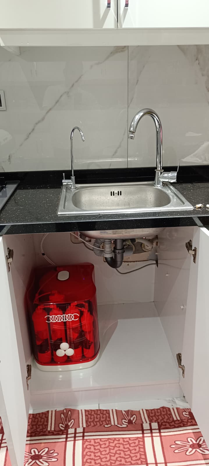 Express Water 12 litre su arıtma cihazının kırmızı gövdeli modeli, mutfak dolabında