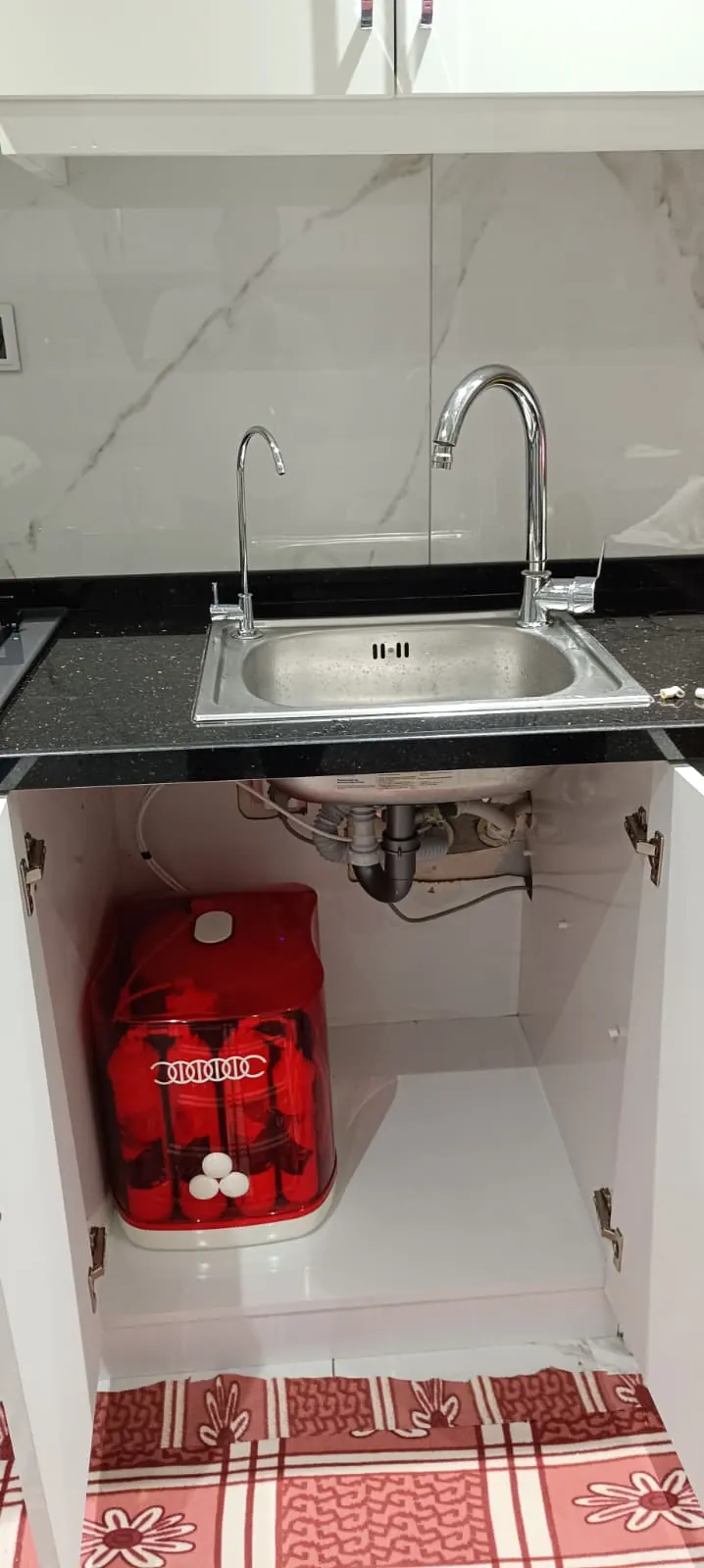 Express Water 12 litre su arıtma cihazının kırmızı gövdeli modeli, mutfak dolabında